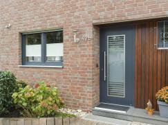 Anthrazitgraue Kunststofffenster und Aluminium-Haustür integrieren sich wunderbar in die Klinkerfassade