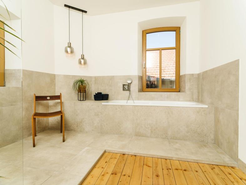 Badezimmer mit Badewanne unterhalb des Holzfensters