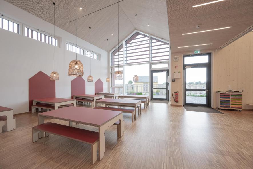 Gruppenraum mit giebelförmiger Pfosten-Riegel-Fensterkonstruktion im Hintergrund