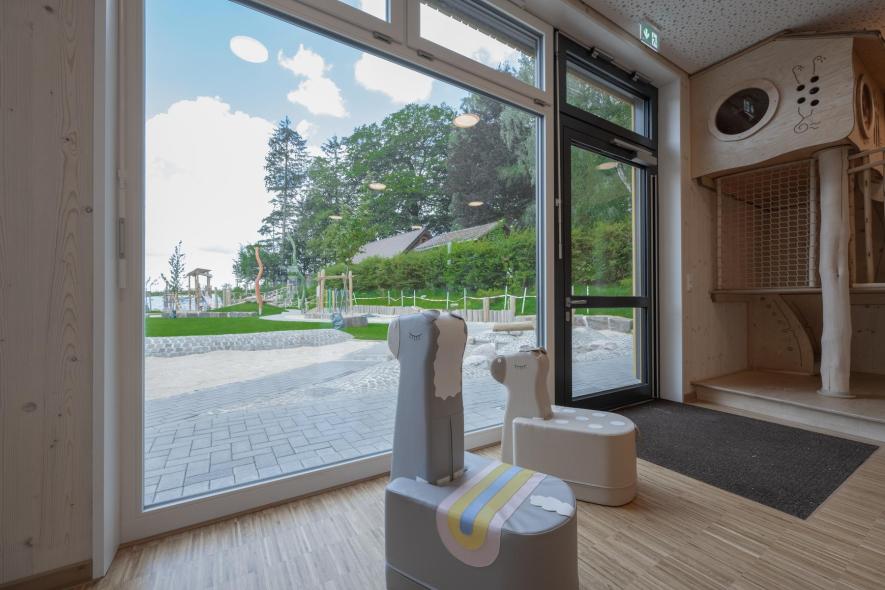 Großflächige Festverglasung mit auswärts öffnender Eingangstür im Erdgeschoss eines Gruppenraums der Kita Sträßchen