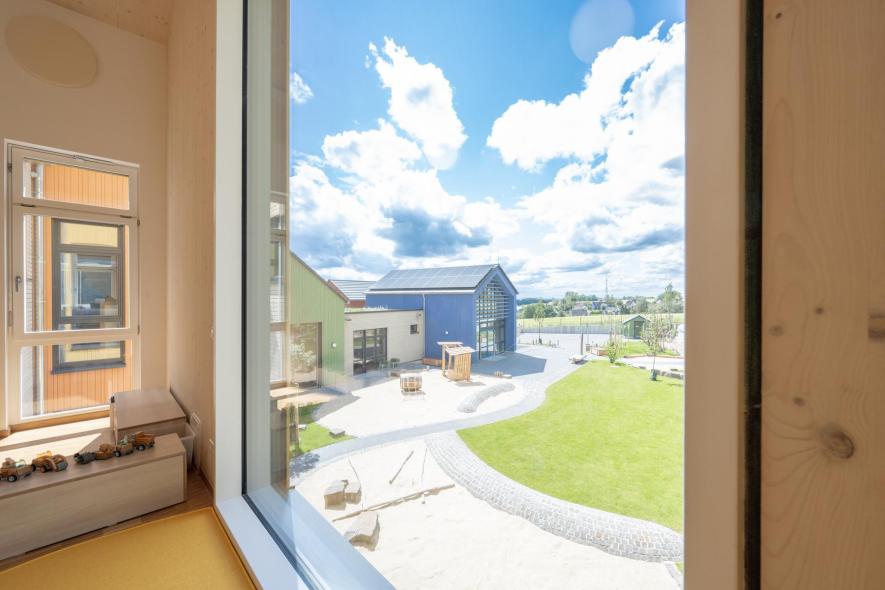 Bodentiefe Festverglasung mit Ausblick auf das gesamte Kitagelände