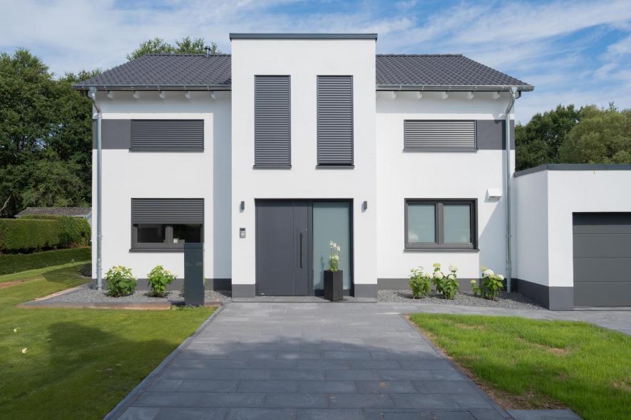 Fassade eines neugebauten Wohnhauses mit Kunststofffenstern in Anthrazit und Raffstore Beschattung