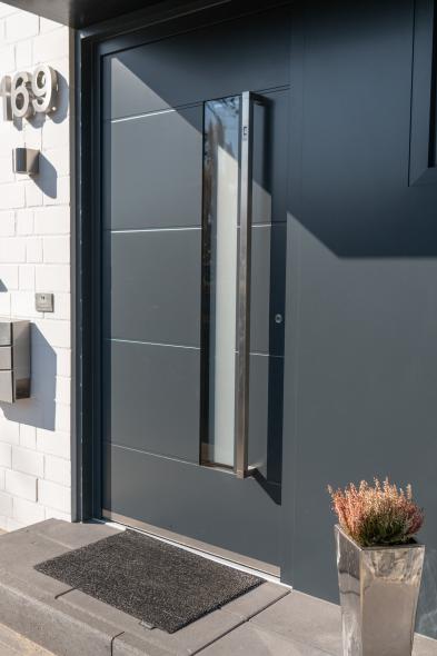 Die Haustür ist mit schmalem Lichtausschnitt und einer im Griff integrierten Fingerscan Öffnung ausgestattet