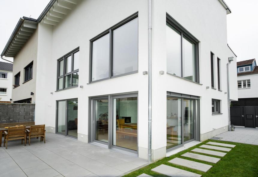 Die grauen Kunststoff-Aluminium-Fenster passen gut zur modernen Fassade