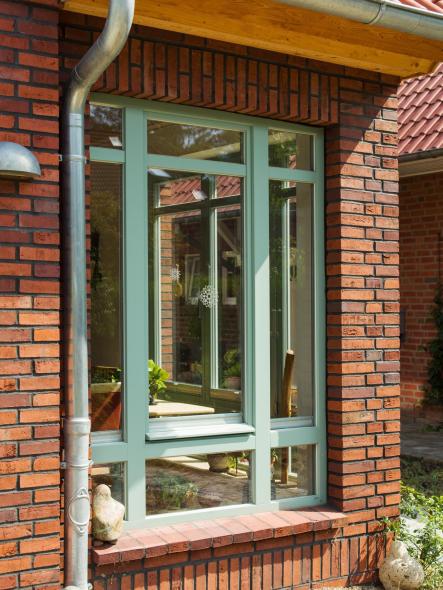 Türkises Holzfenster von PaX in Klinkerfassade