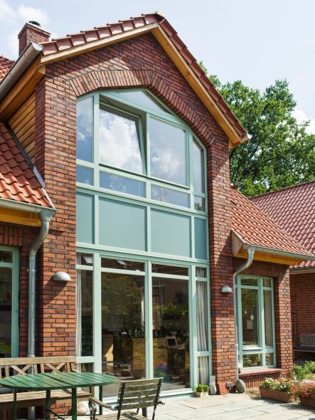 Die türkisen Fenster fügen sich wunderbar in die Klinkerfassade ein