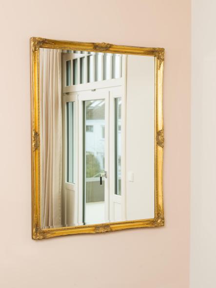 Die edlen Holzfenstern im gold umrahmten Spiegel