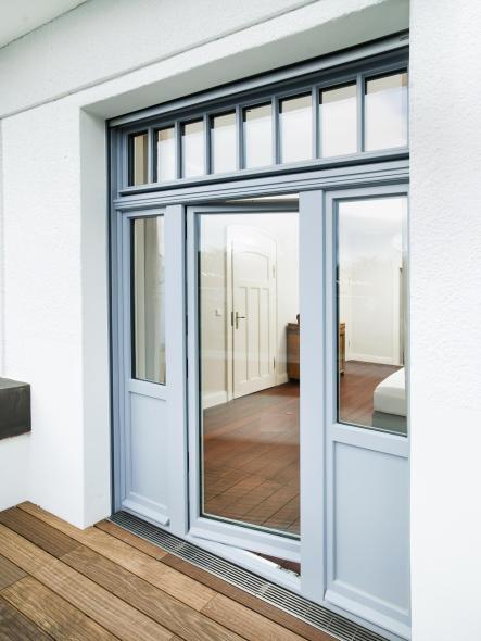 Hellgraue Balkontür aus Holz mit Oberlicht und zwei seitlichen Festelementen