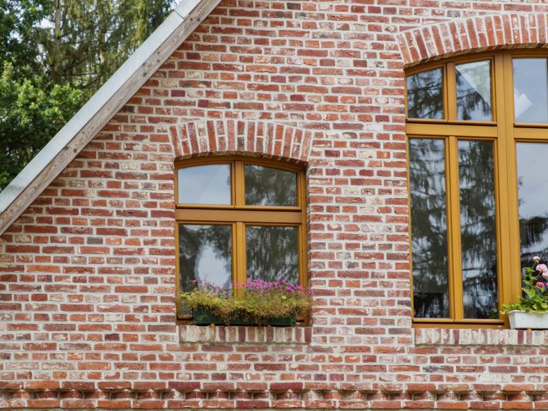 Die Holzfenster im Profil PaXretro mit Lasur Tanne fügen sich wunderbar in die historische Klinkerfassade ein
